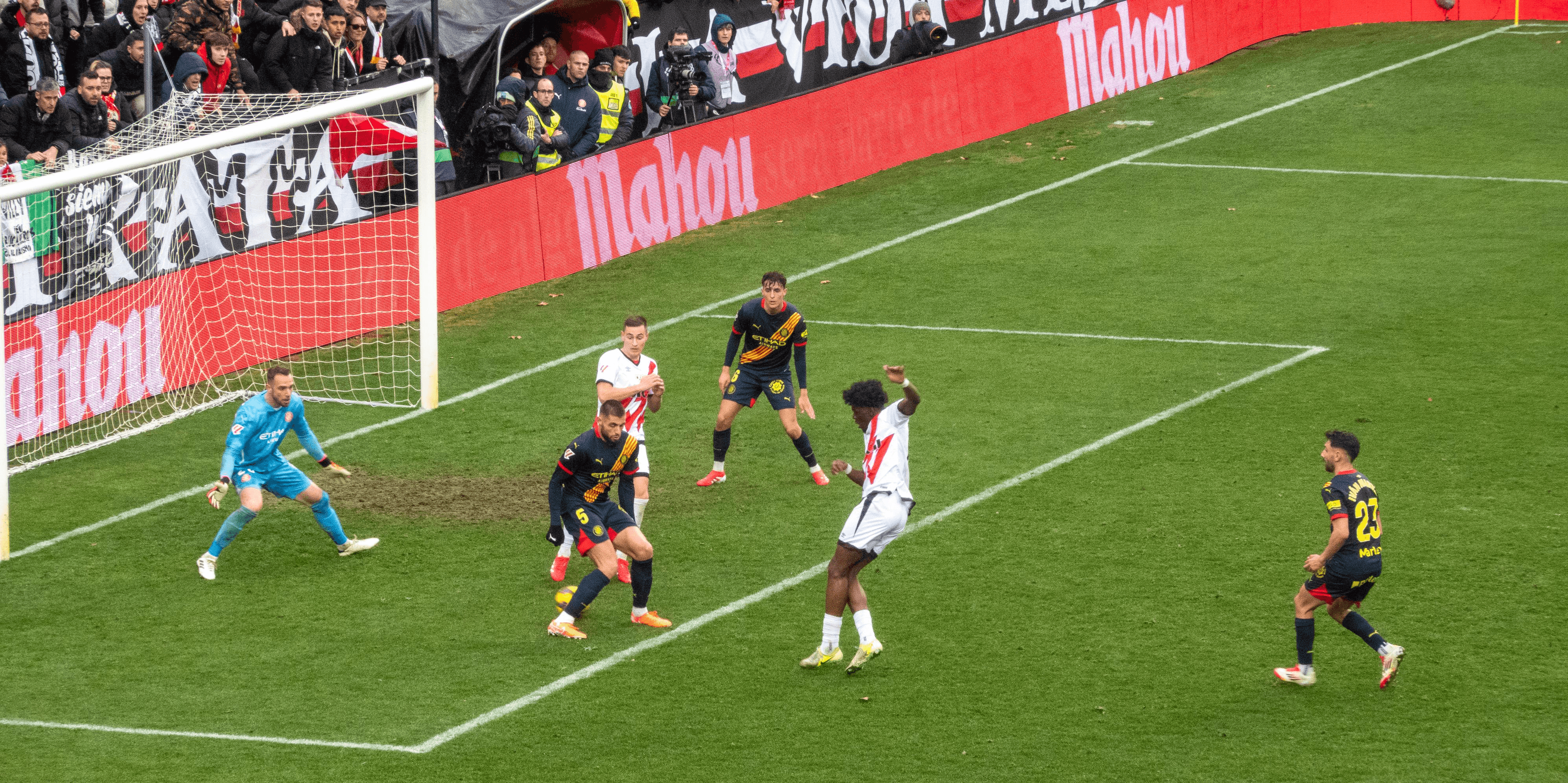 A soccer player prepares to kick the ball in a match, surrounded by opposing players.