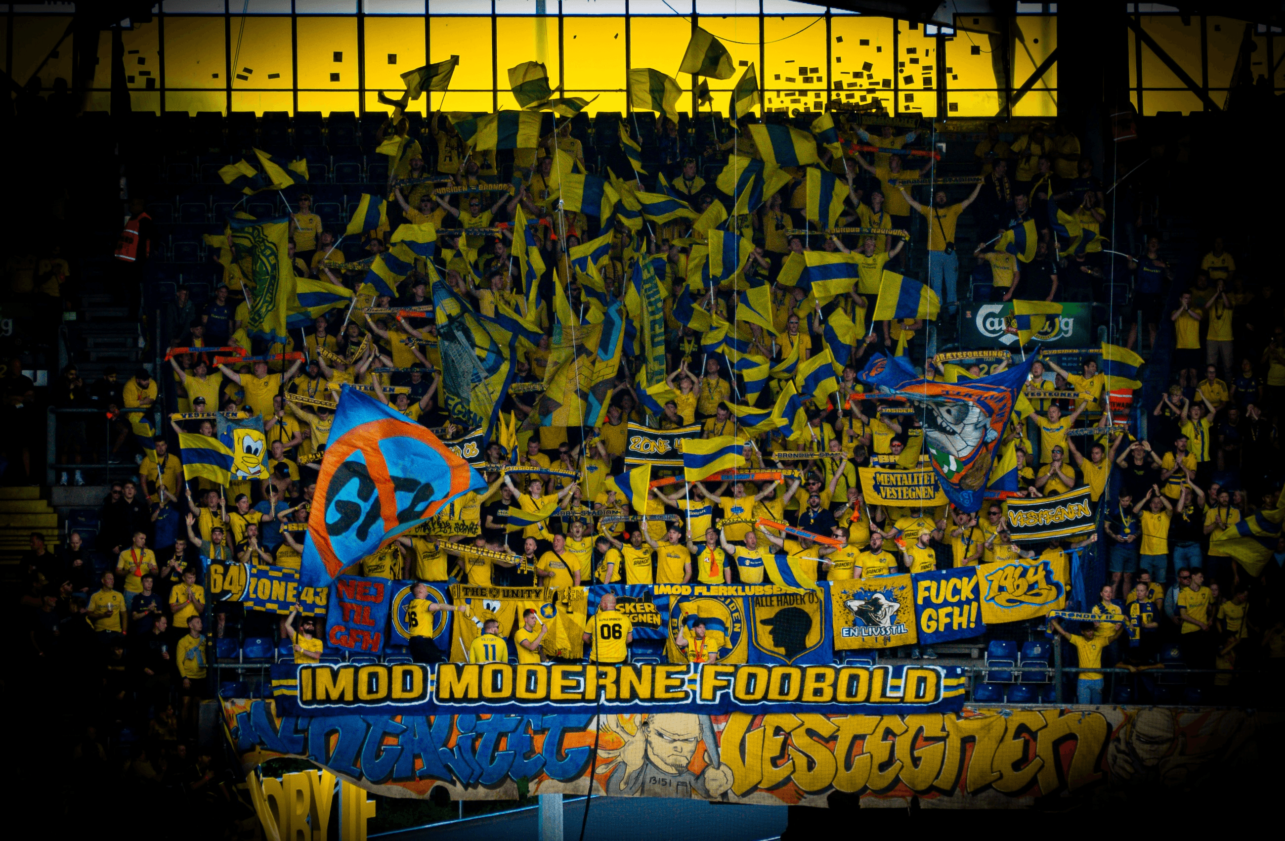 A vibrant crowd of fans waving yellow and blue flags at a sports event.
