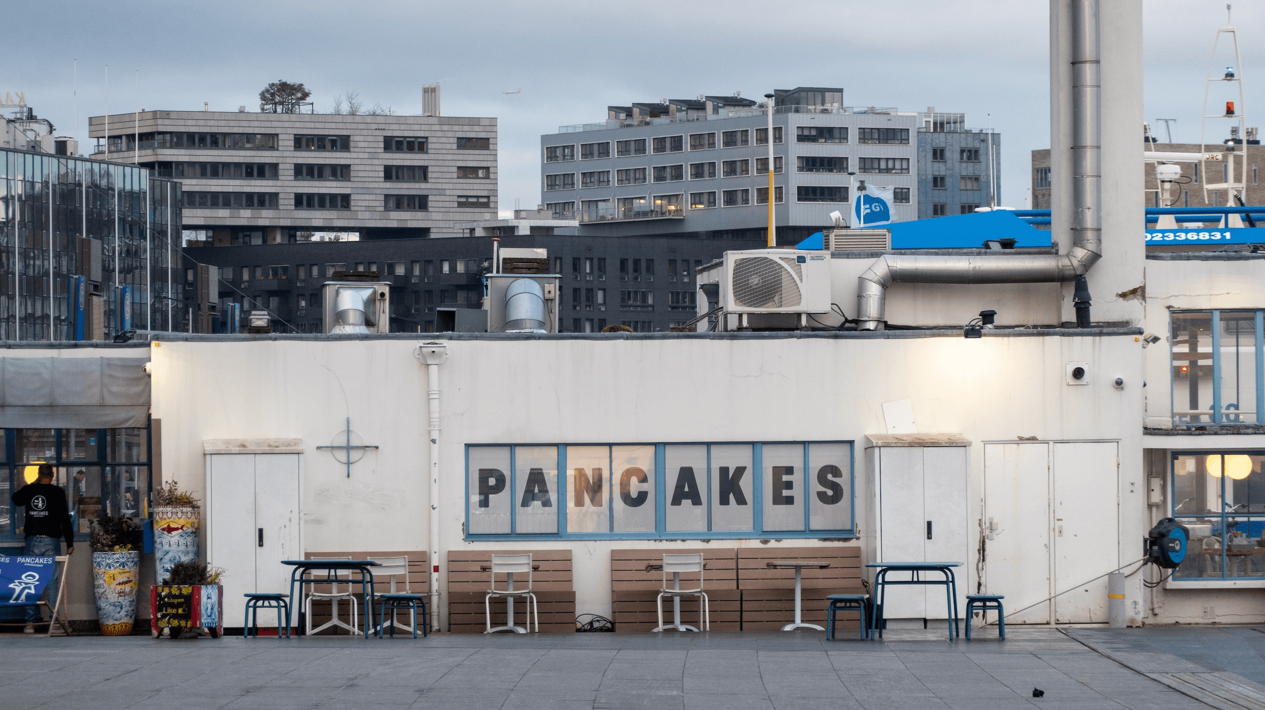 A building facade with "PANCAKES" sign surrounded by urban architecture.