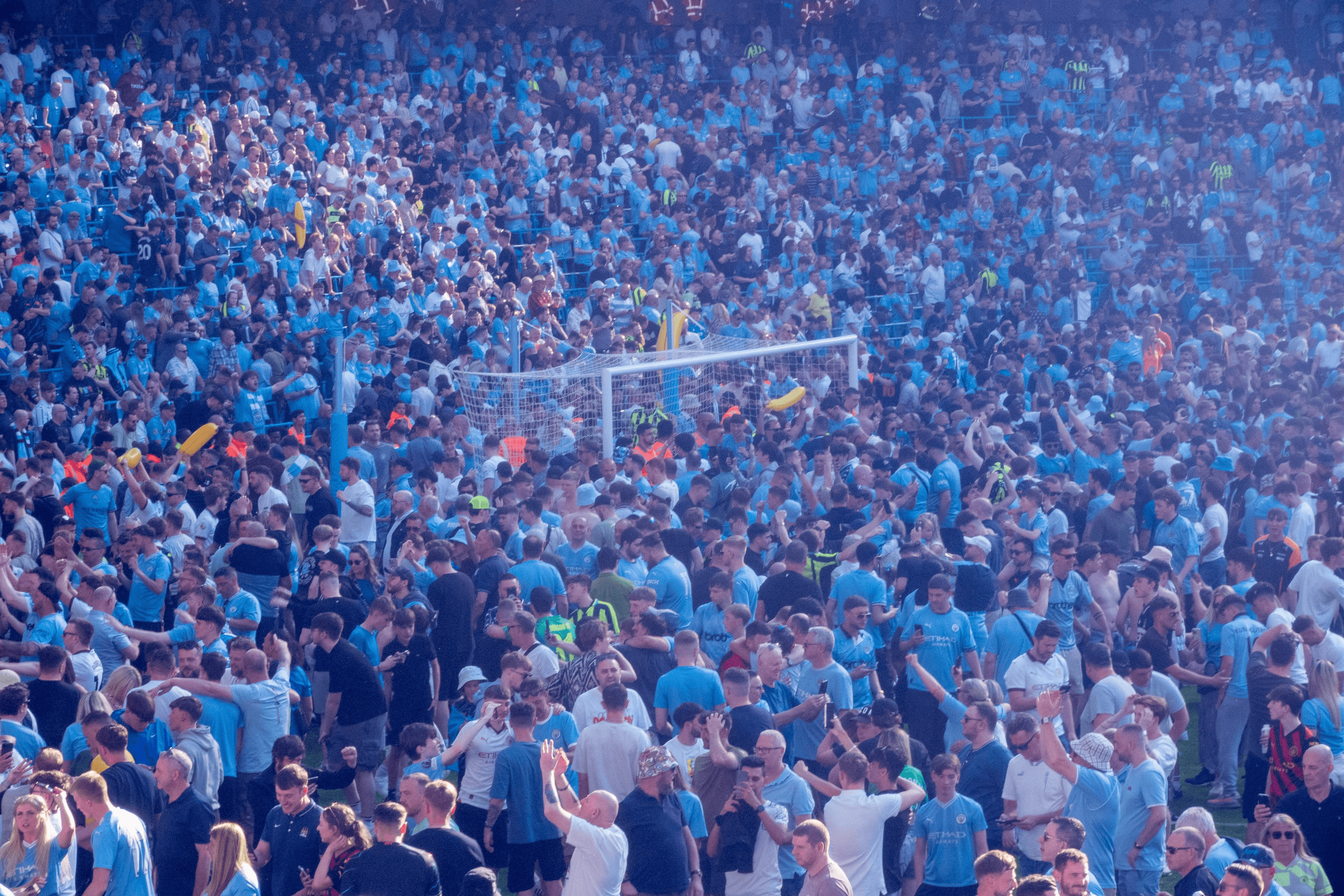 A large crowd of fans in blue shirts celebrating at a sports stadium.
